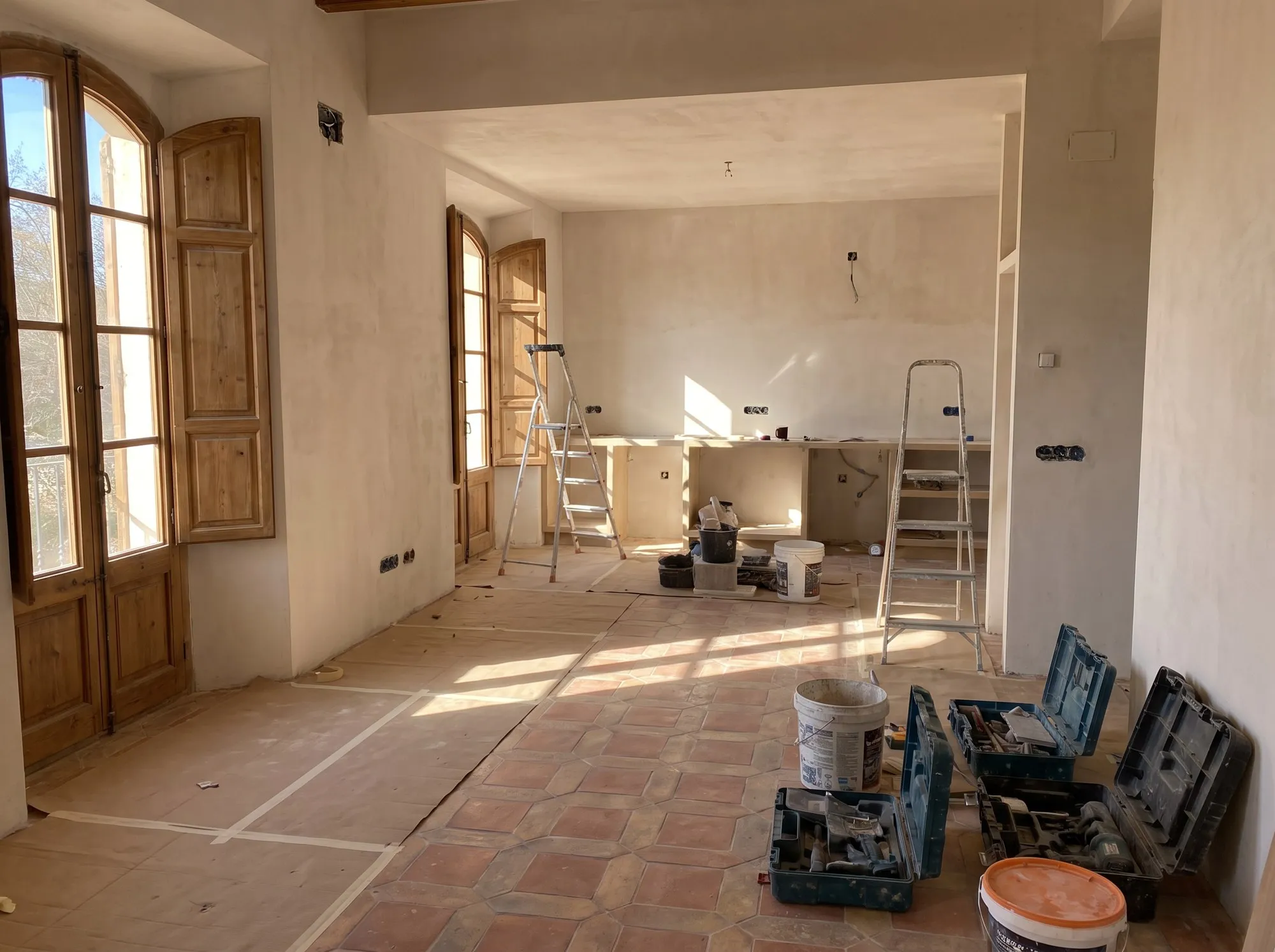 Intérieur de maison en cours de rénovation, sol protégé et murs fraîchement enduits